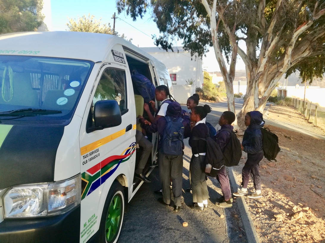 Schoolkinderen stappen in een taxibusje voor schoolvervoer